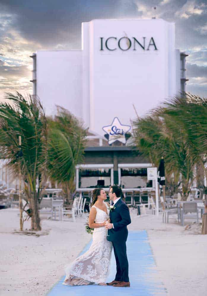 Bride and groom posing in the foreground with the iconic ICONA Diamond Beach wedding in the background.