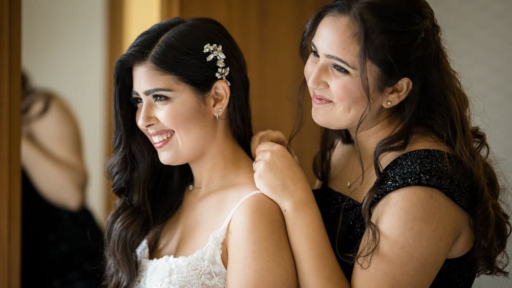 Maid of honor helping bride with her jewelry at Legacy Club at Woodcrest in Cherry Hill NJ