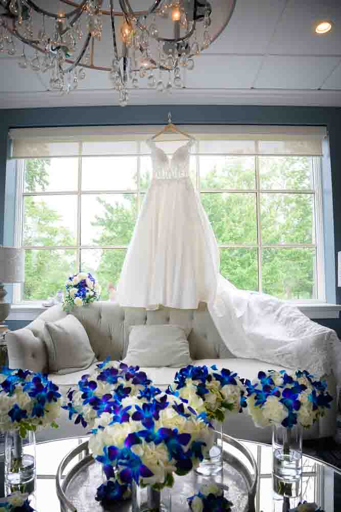 Bridal gown hangin in front of the wind with the bridesmaids flowers in the foreground.