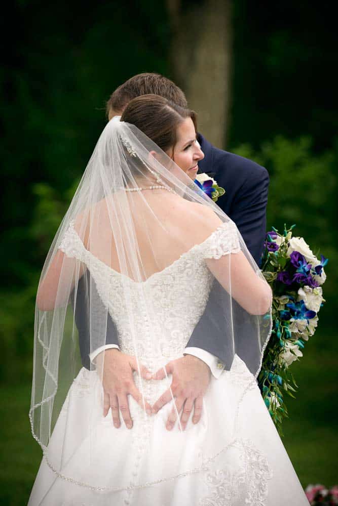 Groom making a heart shape behind the bride at the Hainsport NJ wedding.