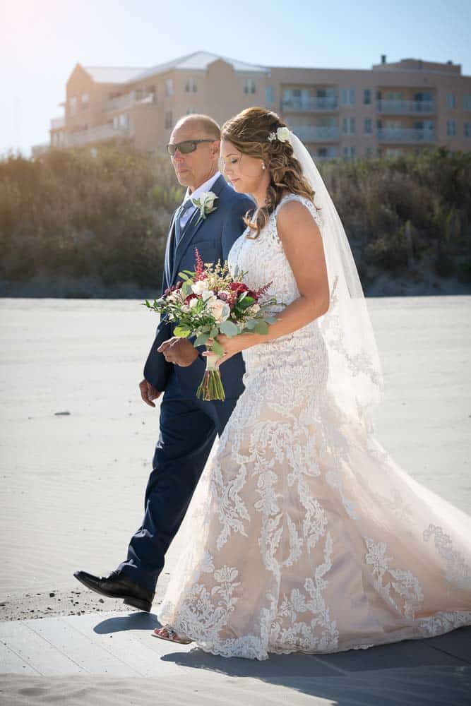 Bride being escorted down the aisle by her father at the ICONA Diamond Beach Wedding.