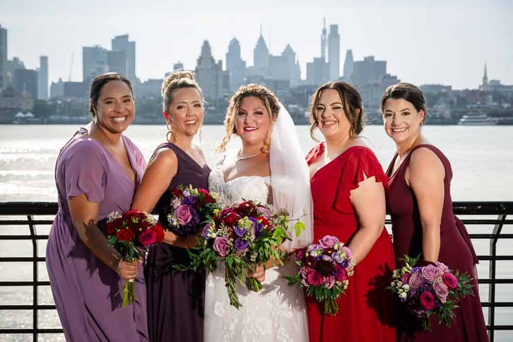 Bridesmaids posing in front of the Delaware river with the City of Philadelphia in the background.