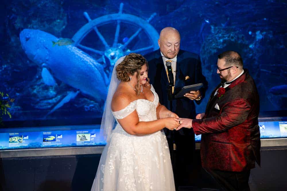 Bride and Groom exchanging rings during the Adventure Aquarium wedding ceremony.