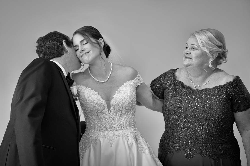 Black and white image with the brides father embracing her as her mother looks on at Bradford Estate