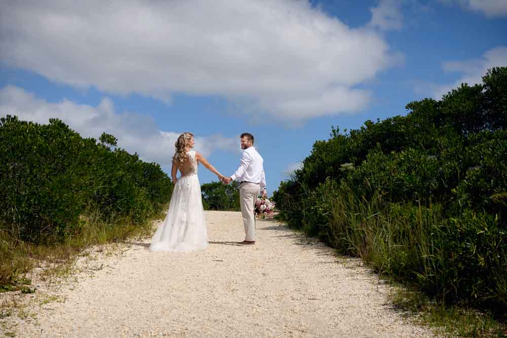 Bride and groom walking toward the cape may beach