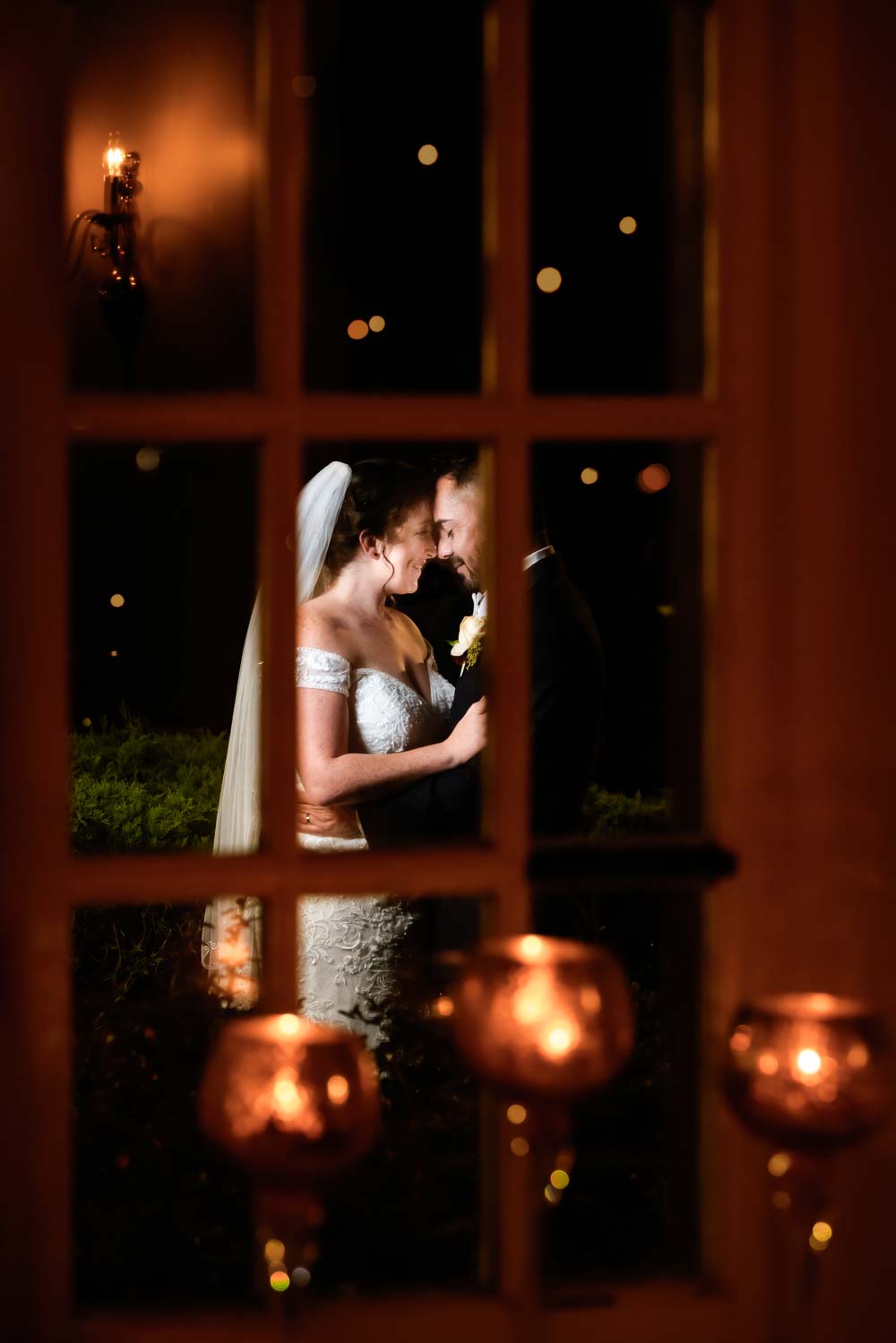 Bride and groom photographed through the venues ballroom window at Braddocks Tavern in Medford NJ.