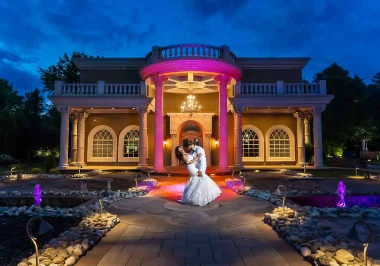 Groom dips wife in front of Brigalias Chapel during sunset.