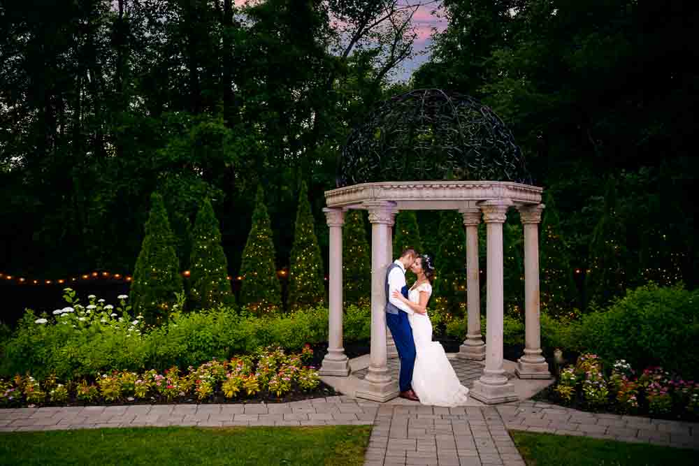 Couple posing in front of gazebo as the sun sets.