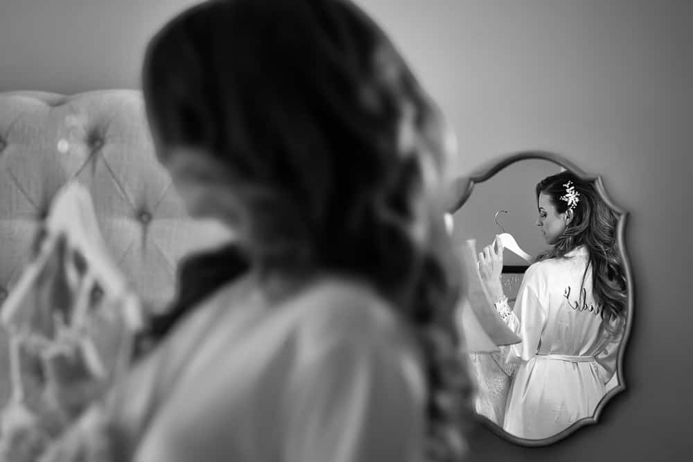 Bride hold on to the gown and image focused on the mirror at the Merion in Cinnaminson NJ