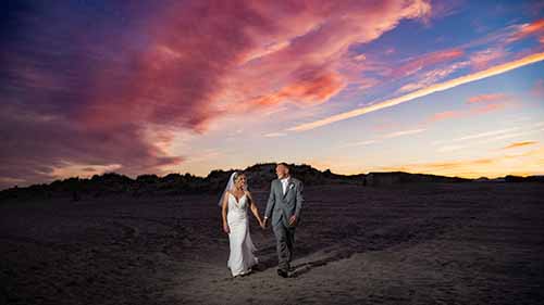 Bride and groom walking on the beach during sunset at ICONA Windrift in Avalon NJ